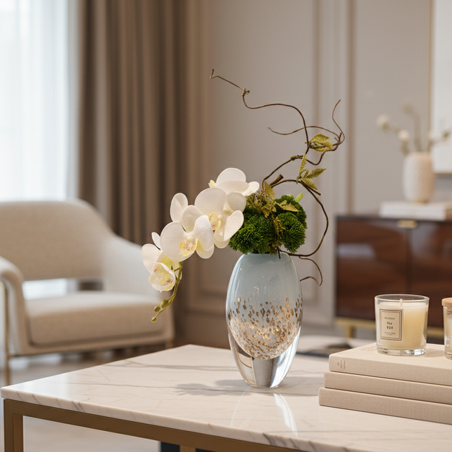 Decorative setup on a table with a vase, candles, and books in a room.