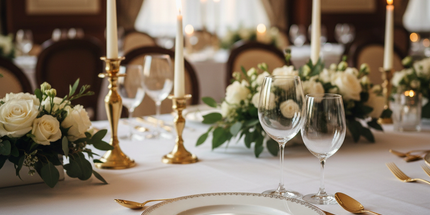 Gold vintage stainless steel cutlery set arranged on a formal dinner table with white linen and fine china — editorial lifestyle view